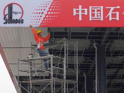 A Chinese worker labors on a Sinopec sign board at a gas station in Huai'an, eastern