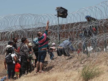 Migrants cross a barbed-wire barrier at the US-Mexico border, as seen from Ciudad Juarez,