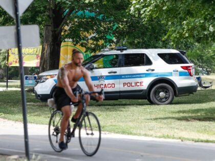 A man bikes past a Chicago Police officer monitoring North Avenue Beach area in Chicago, Illinois, on June 18, 2021. - Businesses and restaurants in downtown Chicago that survived the pandemic-related economic slump, as well as two spasms of looting last summer, should be ecstatic with Monday's reopening of America's …