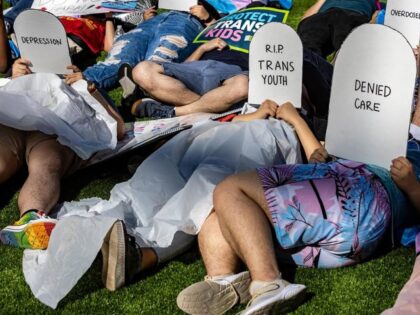 Protesters lie on the ground holding cardboard signs shaped like tombstones in front of the Marriott Fort Lauderdale Airport as the Florida Board of Medicine meets inside on Aug 5, 2022. On the agenda is a discussion about a proposed rule by Gov. Ron DeSantis’s administration to ban doctors from …
