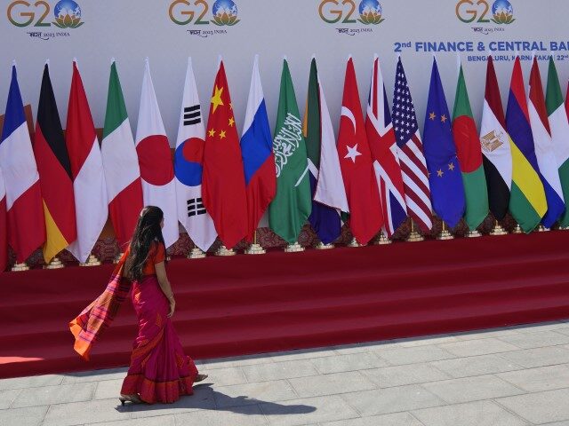 FILE- A delegate walks past a display of flags of participating countries at the venue of