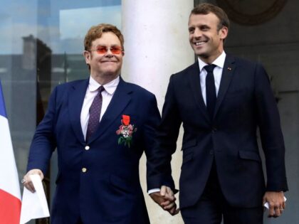 TOPSHOT - French President Emmanuel Macron (R) and British singer-songwriter Elton John arrive to speak to a crowd in the courtyard of the Elysee Palace in Paris, on June 21, 2019, as part of a ceremony to award John of the French Legion of Honour and concerts to mark France's …