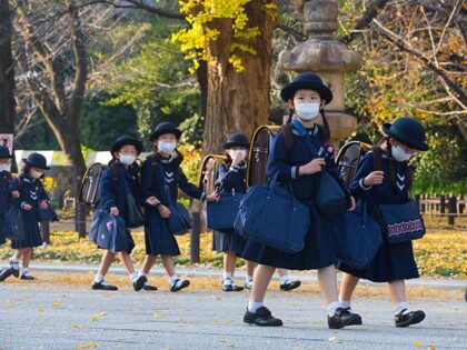 Japanese elementary school girls students dressed in traditional uniforms while wearing face masks walk back home after their lessons. (Photo by Stanislav Kogiku/SOPA Images/LightRocket via Getty Images)