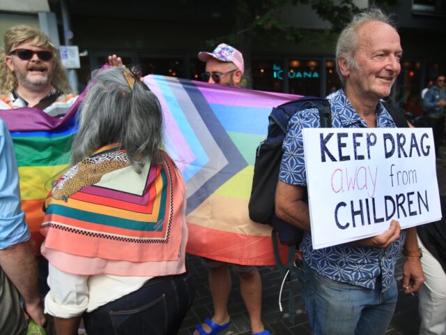 BRIGHTON, ENGLAND - AUGUST 04: A protester against drag queens reading to children holds a sign saying 'Keep Drag Away From Kids' as both protesting groups come together outside Jubilee library on August 04, 2022 in Brighton, United Kingdom. Drag Queen Story Hour, an established and ticketed children's entertainment provider, …
