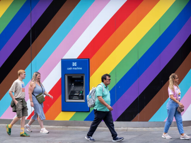 People interact with a large wall outside a high street bank emblazoned with the colours o