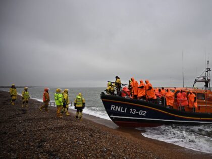 Migrants, picked up at sea attempting to cross the English Channel, wait to be helped asho