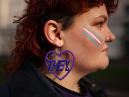 Trans rights activist Lilly wears an earring featuring a 'they' pronoun symbol, during a p