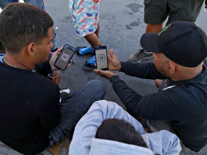 Venezuelan migrants browse the CBP One mobile app searching for an appointment to enter th