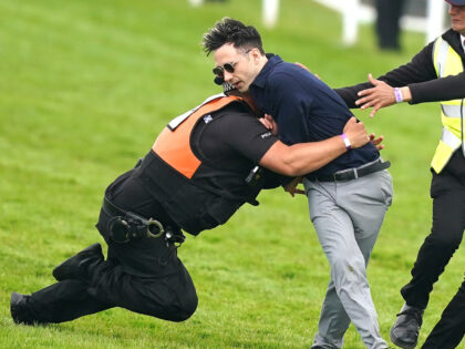 A protestor is tackled by police and stewards during the Betfred Derby during Derby Day of