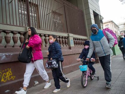 Parents walk their children -wearing face masks- to the Sagrado Corazon school on Santiago