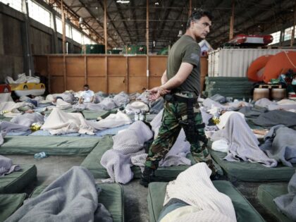 A member of the Coastguard overlooks suvivors as they rest in a warehouse used as a tempor
