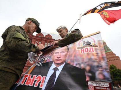 TOPSHOT - Activists hold a portrait of Russian President Vladimir Putin near Red Square in