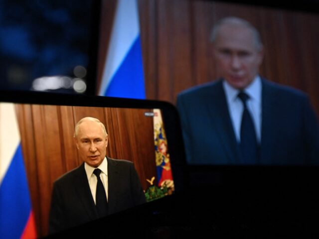 This photograph shows Russia's President Vladimir Putin, seen on a smartphone screen and a