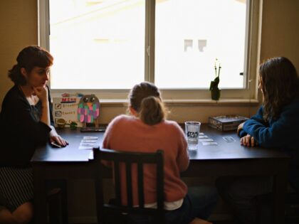 WHEAT RIDGE, CO - FEBRUARY 26 : From left, Whitney Nichols, 39, plays a card game with her children Cambria Nichols- Dewey, 12, and Ember Nichols- Dewey, 14, at their home in Wheat Ridge, Colorado on Friday, February 26, 2021. Whitney is single mother of three who has been self-employed, …