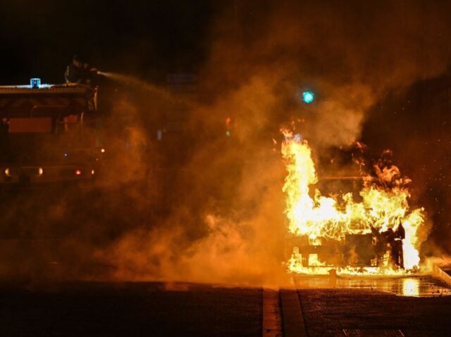 A French firefighter puts out the flames of a burning car in Floirac on the outskirts of B