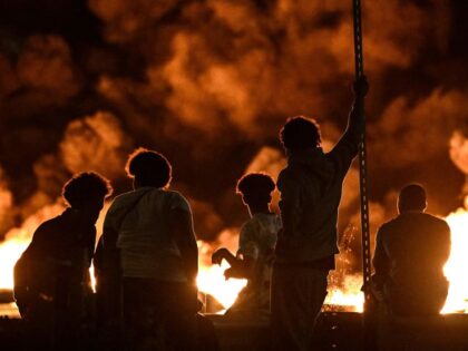 TOPSHOT - People look at burning tyres blocking a street in Bordeaux,, south-western Franc