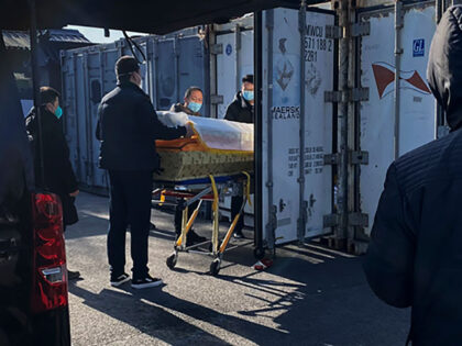 A coffin is loaded from a hearse into a storage container at the Dongjiao crematorium and