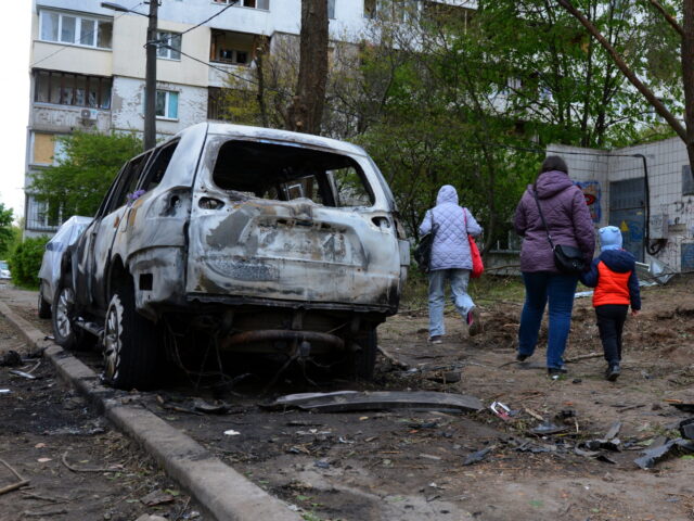 KYIV, UKRAINE – MAY 8: People walk past cars wrecked by the fall of the downed Shahed kamikaze drone on May 8, 2023 in Kyiv, Ukraine. In Kyiv, the downed Shahed kamikaze drones fell in several districts of the city, damaging residential buildings, cars, and the roadway. (Photo by Oleksandr …