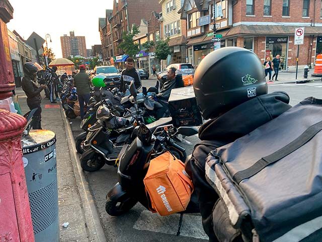 Large group of delivery people waiting on street with motorcycles, Queens, New York. (Phot