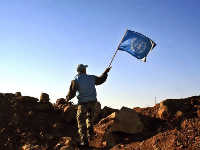 A UN Indian soldier waves the UN flag at the outskirts of the Lebanese village of al-Ghaja