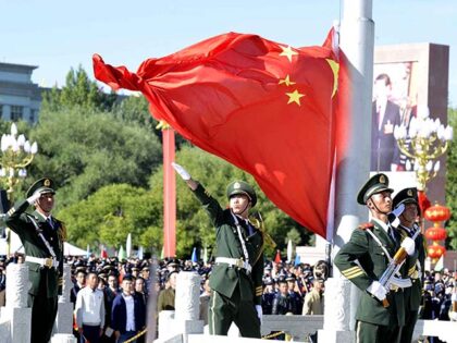 Chinese paramilitary police conduct a flag rising ceremony as thousands of people gather in front o
