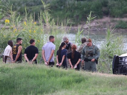 Texas and Florida Highway Patrol troopers arrest a group of migrants along the Rio Grande in Eagle Pass, Texas. (Randy Clark/Breitbart Texas)