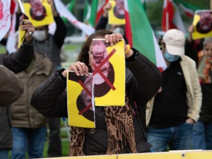 21 September 2021, Berlin: A woman tears up a picture of Iranian President Ebrahim Raisi a