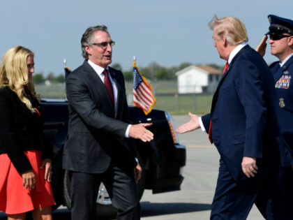 President Donald Trump reaches out to shake hands with North Dakota Gov. Doug Burgum, and
