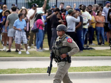 A law enforcement officer walks as people are evacuated from a shopping center where a shooting occurred Saturday, May 6, 2023, in Allen, Texas. (AP Photo/LM Otero)