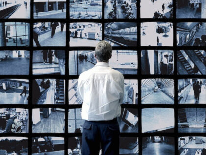 Man watching wall of surveillance screens - stock photo
