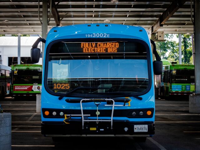 SILVER SPRING, MD - JUNE 29: A brand new electric bus, right, sits across from a row of fossil fuel versions resting in the shade of solar panels as Montgomery County nears completion on construction on its micro-grid enabled electric bus terminal, in Silver Spring, MD. (Photo by Bill O'Leary/The …