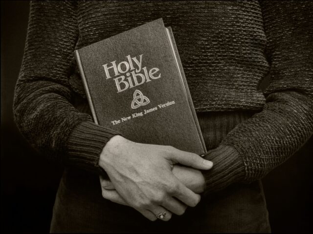 Close-up of a copy of the New King James Version of the Bible in the hands of an unidentif