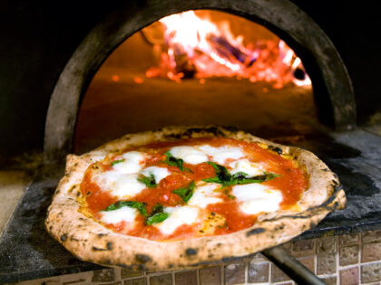 UNITED STATES - JUNE 02: Roberto Caporuscio holds a margherita pizza in front of the wood fired oven in the kitchen of Keste in New York, U.S., on June 2, 2009. The West Village restaurant is run by the U.S. head of the Associazione Pizzaiuoli Napoletani. The organization has a …