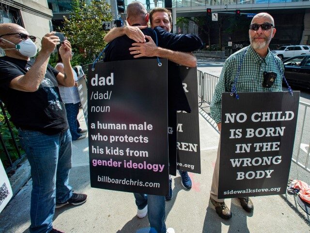Anti-trans activist Chris Elston embraces a supporter as he demonstrates against gender affirmation treatments and surgeries on minors, outside of Boston Childrens Hospital in Boston, Massachusetts, on September 18, 2022. - Protestors for and against the hospital's programs that deal with gender affirmation surgeries and hormonal treatments were gathered outside …