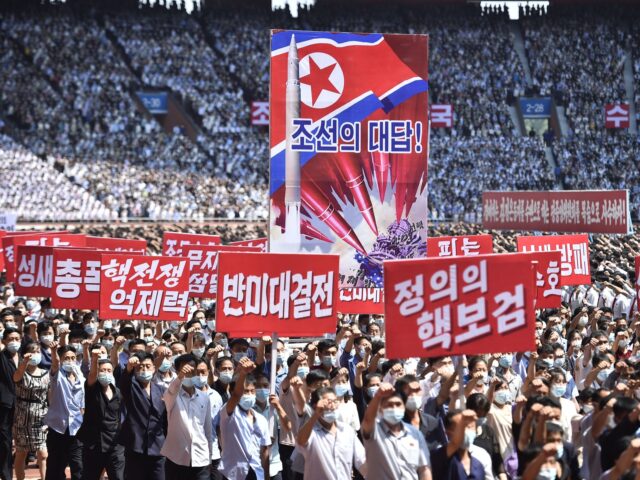 TOPSHOT - In this photo taken on June 25, 2023, residents of Pyongyang hold banners that r