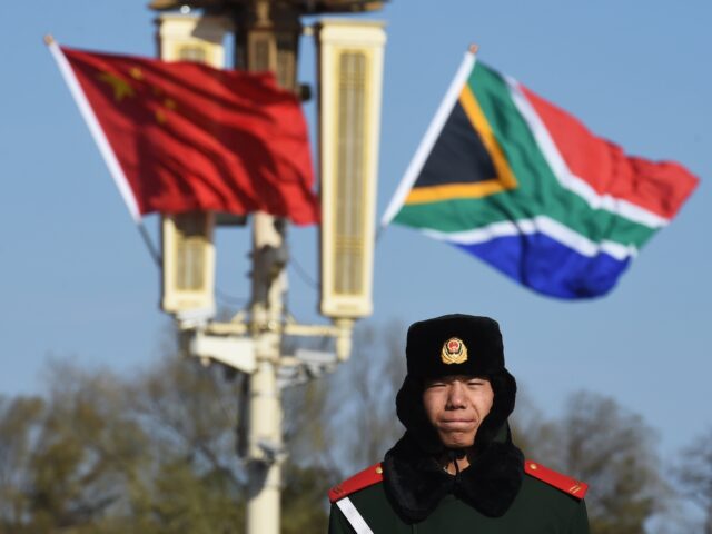 A Chinese paramilitary policeman stands in front of the South African flag (R) and Chinese