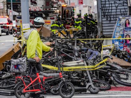 A biker stops to look at a pile of e-bikes in the aftermath of a fire in Chinatown, which authorities say started at an e-bike shop and spread to upper-floor apartments, Tuesday June 20, 2023, in New York. (AP Photo/Bebeto Matthews)