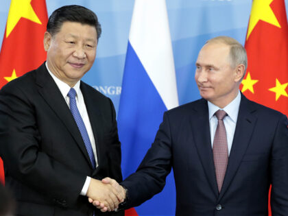 Biden - Russia's President Vladimir Putin (R) shakes hands with his China's counterpart Xi