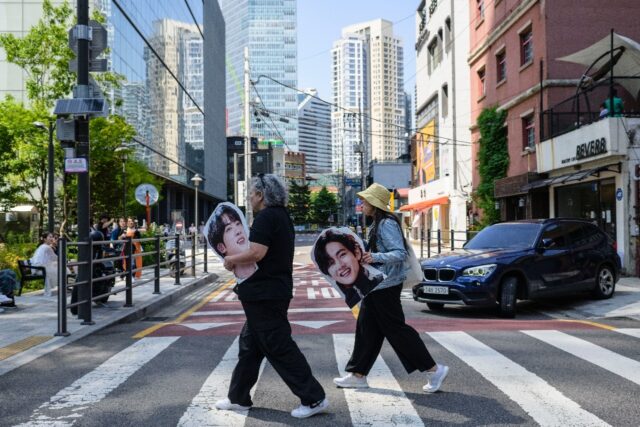 Australian fans of BTS carry cardboard cutouts of the group members in Seoul on Tuesday