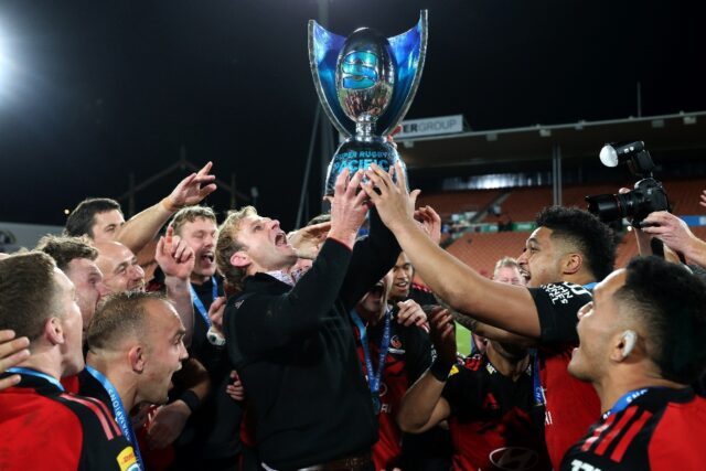 Crusaders coach Scott Robertson (centre) lifts the Super Rugby Pacific trophy after Saturd