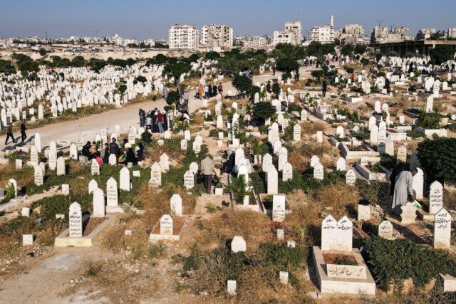 People visit the graves of loved ones at a cemetery on the first day of the Muslim feast o
