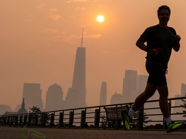 JERSEY CITY, NEW JERSEY - JUNE 8: The One World Trade Center and the New York skyline is seen in the background as a man jogs through the Liberty State Park while the smoke from Canada wildfires covers the Manhattan borough on June 8, 2023 in New Jersey. (Photo by …