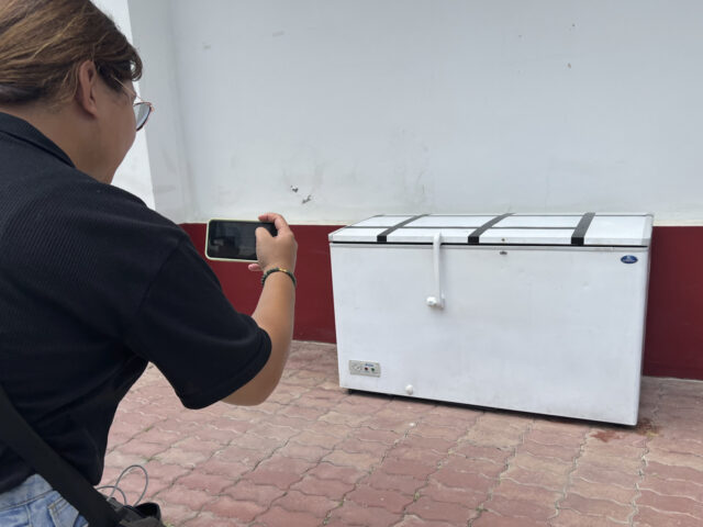 A Thai reporter takes a photo of an empty freezer at the Nong Prue police station in Patta
