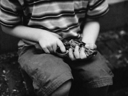 Child holding gun, mid-section, b&w - stock photo