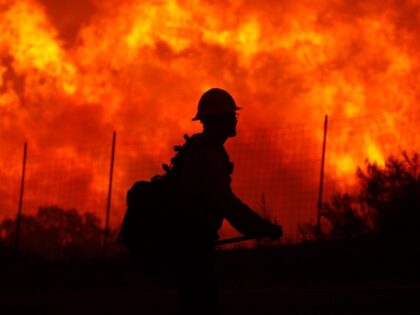 LAKE HUGHES, CA - JUNE 1: Flames rise near a firefighter as the Powerhouse fire makes a fa