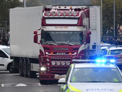 Police officers drive away a lorry (C) in which 39 dead bodies were discovered sparking a murder investigation at Waterglade Industrial Park in Grays, east of London, on October 23, 2019. - British police said 39 bodies were found near London Wednesday in the container of a truck thought to …