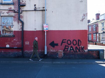 A man walks past a terraced house, the walls of which bare graffiti reading "food bank" and an arrow pointing in the direction of a community food bank program, in Harehills, one of the most deprived areas in Leeds, as living standards think tank Resolution Foundation warns that the UK's …