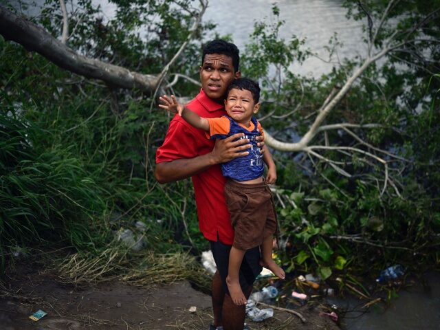 TOPSHOT - A migrant carrying a child tries to get to the US through the Rio Grande River as seen from Matamoros, state of Tamaulipas, Mexico, on May 11, 2023. Pandemic-era controls barring migrants from claiming US asylum expire Thursday night amid fears of chaos at the Mexican border, with …