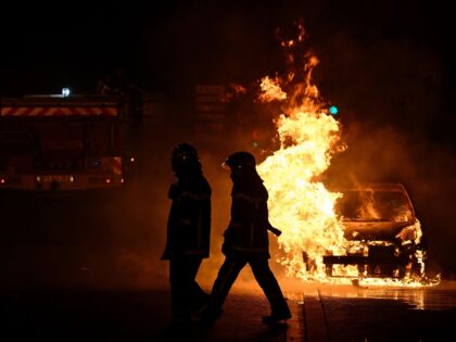 French firefighters walk past a burning car in Floirac on the outskirts of Bordeaux, south-western France on late June 29, 2023, during riots and incidents nationwide after the killing of a 17-year-old boy by a police officer's gunshot following a refusal to comply in a western suburb of Paris. (Photo …