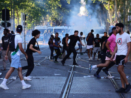 TOPSHOT - Protesters run from launched tear gas canisters during clashes with police in Ma